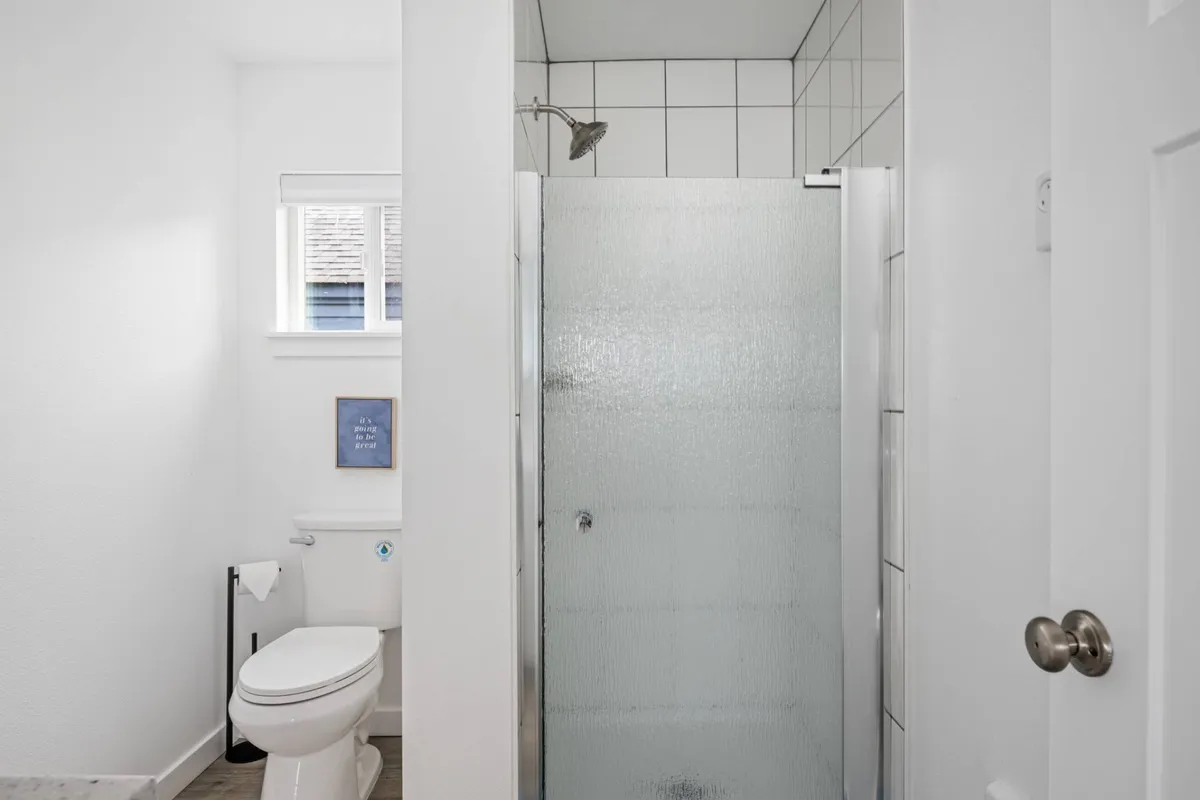 A calm, spa-inspired bathroom featuring a modern shower area, toilet, and decorative wall art. The space is accented by clean lines and soothing tones, conveying an atmosphere of relaxation and refreshment.